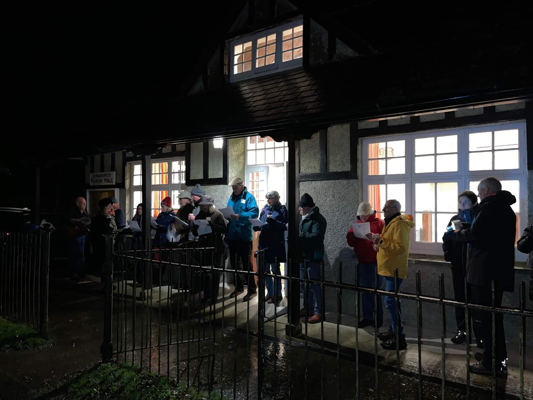 a group of people out side the hall singing in the dark 